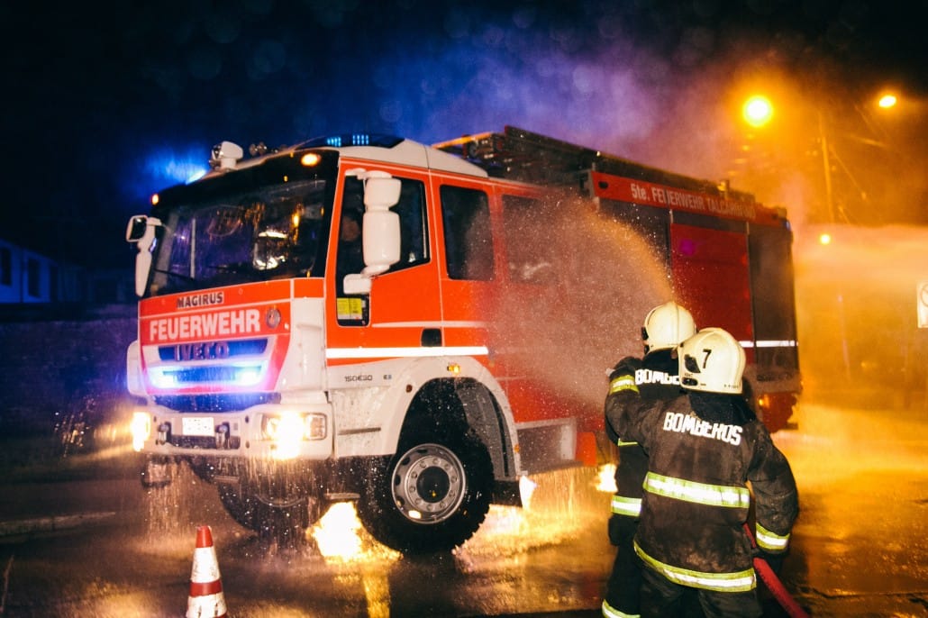 Unidad B-5 con balizas encendidas y voluntarios lanzando agua en un trabajo nocturno