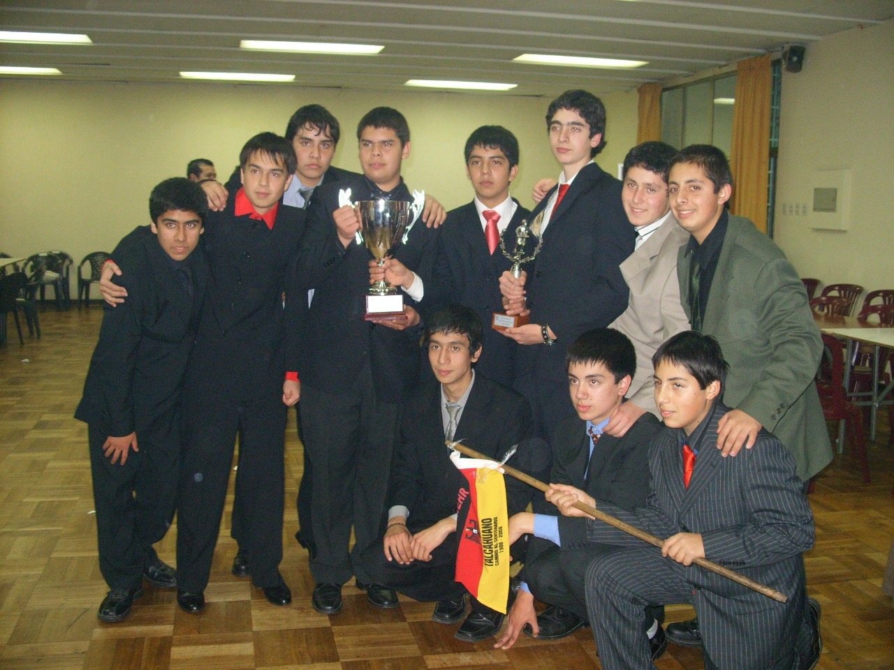 Cadetes de terno celebrando con dos copas y el banderín «Talcahuano, camino al centenario 1908-2008»
